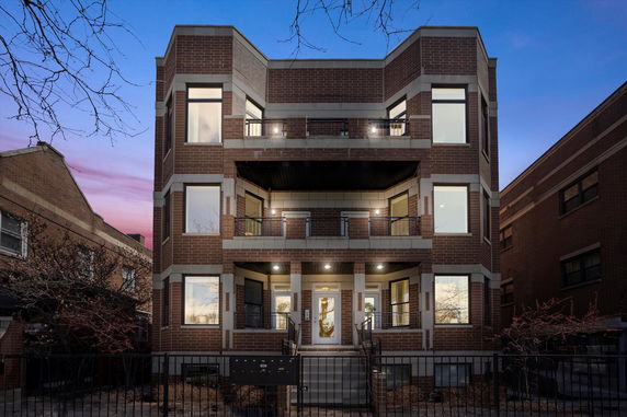 Front view of a three-story building with brick exterior and balconies.