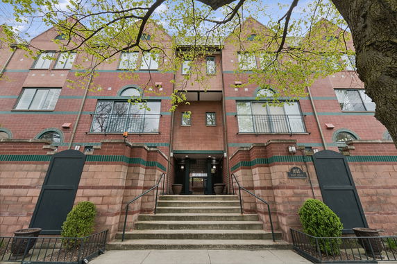 Front view of a multi-story brick building with steps leading to the entrance.