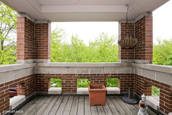 Rooftop area with brick walls, planters, and a wooden floor.