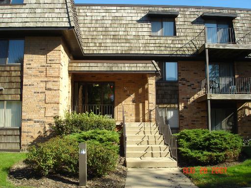 Front view of a multi-story building with brick exterior and a central entrance with stairs.