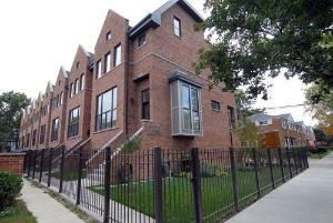 Front view of a brick townhouse with multiple stories and bay windows.