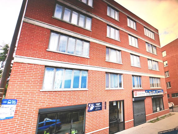 Front view of a multi-story brick building with multiple windows.