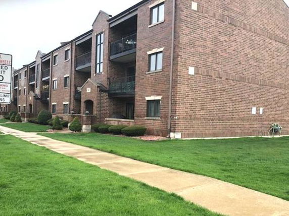 Front view of a multi-story brick residential building with balconies.
