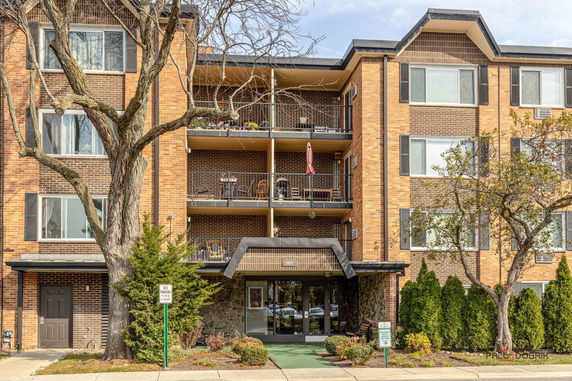 Front view of a multi-story brick apartment building with balconies.