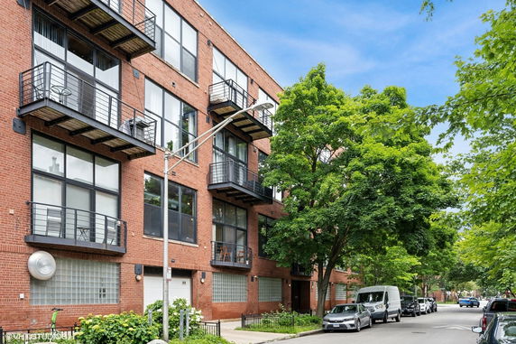 Front view of a multi-story brick building with balconies and large windows.