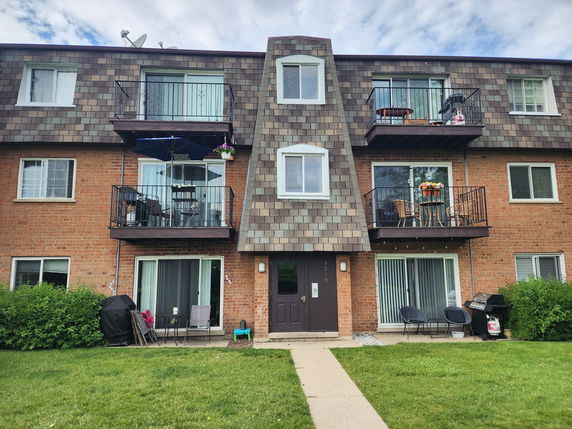 Front view of a three-story apartment building with balconies and a central entrance.