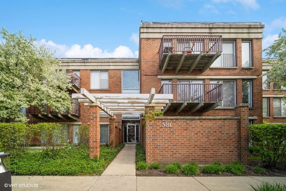 Front view of a two-story brick apartment building with balconies and a central entrance.
