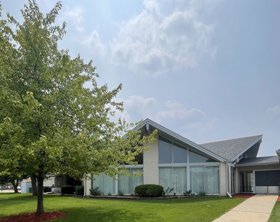 Front view of a modern single-story building with large windows and a sloped roof.