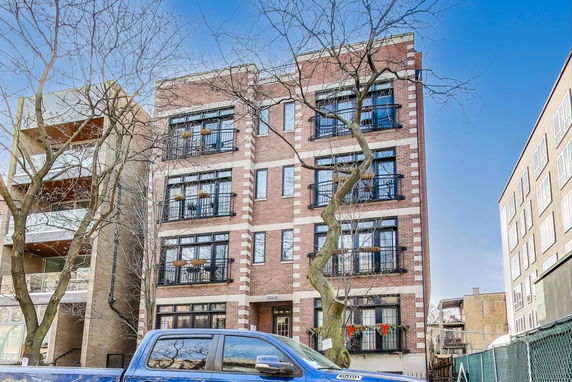 Front view of a multi-story brick building with large windows.