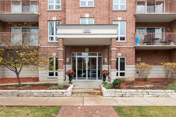 Front view of a brick building with multiple balconies and a central entrance.