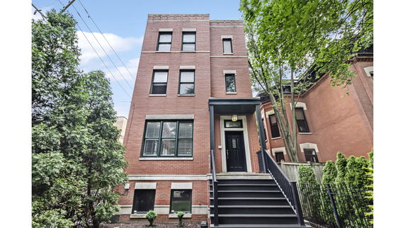 Front view of a three-story brick building with a main entrance and a staircase.