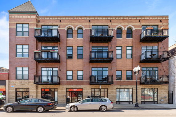 Front view of a multi-story brick apartment building with balconies.