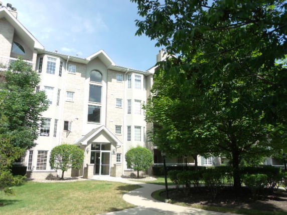 Front view of a multi-story residential building with a gabled entrance.