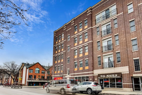Front view of a multi-story brick building with businesses on the ground floor.