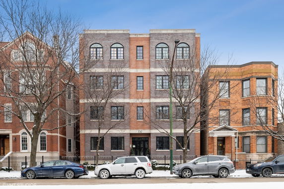 Front view of a multi-story brick building with large windows.
