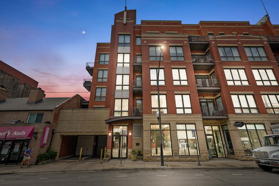 Front view of a multi-story brick building with large windows and balconies.