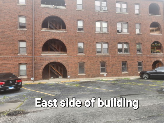 Side view of a brick residential building with arched balconies.