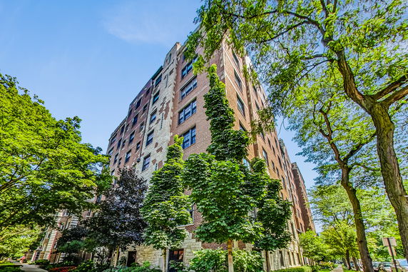 Front view of a multi-story brick building with greenery.