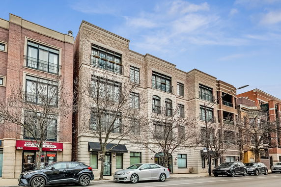 Front view of a multi-story brick building with large windows and storefronts on the ground floor.