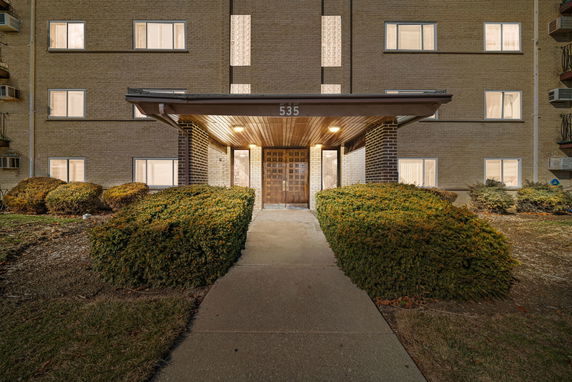 Front view of a multi-story building with a brick facade and wooden entrance.