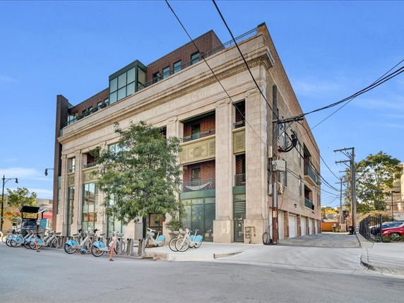Front view of a multi-story building with large columns and bicycles parked outside.