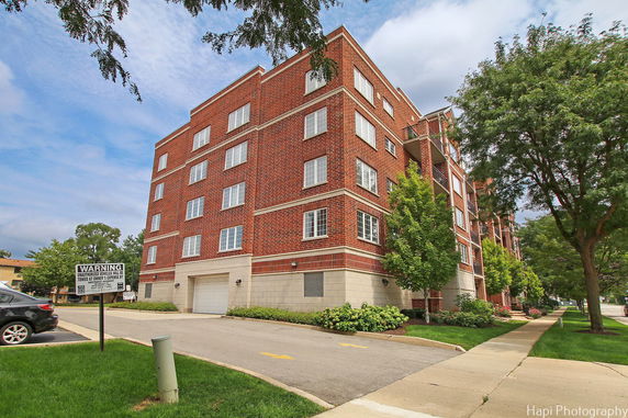 Front view of a multi-story brick apartment building with multiple windows and a garage entrance.