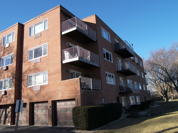 Front view of a multi-story brick apartment building with balconies.