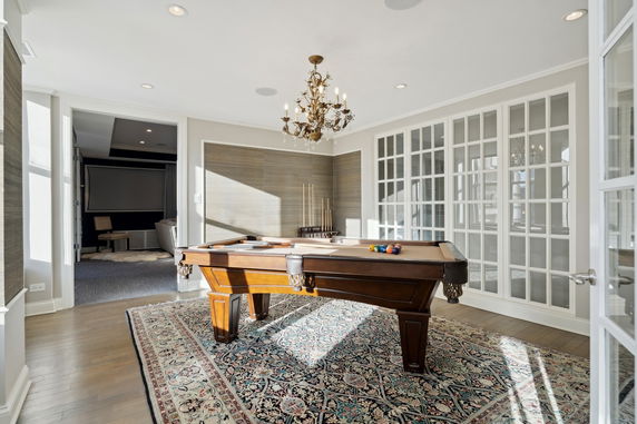 Room with a billiards table and chandelier.