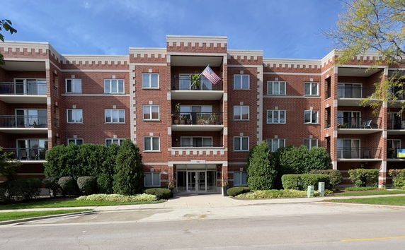 Front view of a multi-story brick apartment building with balconies.