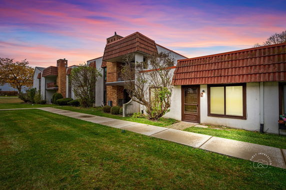 Front view of a multi-story building with brick and stucco exterior under a sunset sky.
