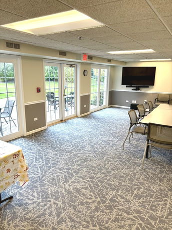 Interior of a recreational room with chairs, tables, and a television.