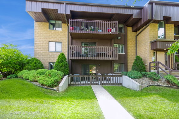 Front view of a multi-story apartment building with balconies and landscaped surroundings.