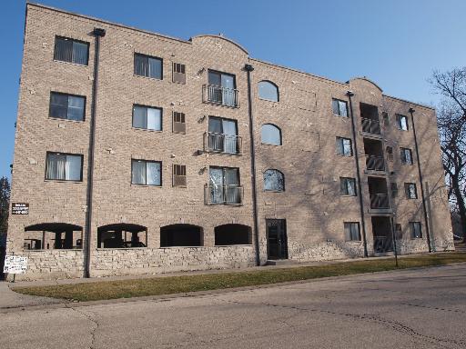 Front view of a multi-story apartment building with brick exterior and several windows.
