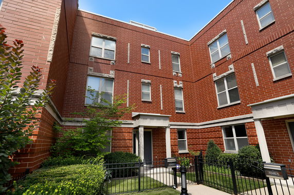 Front view of a multi-story brick building with multiple windows and a small gated entrance.