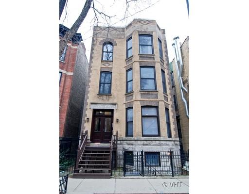Front view of a three-story brick building with a staircase leading to the entrance.