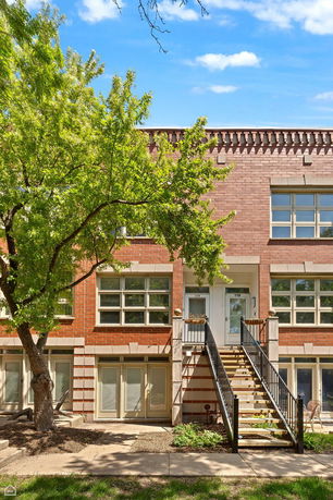 Front view of a two-story brick townhouse with stairs leading to the main entrance.