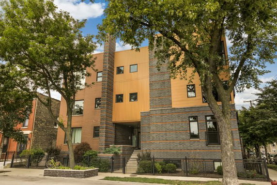 Front view of a multi-story building with a combination of brick and orange paneling.