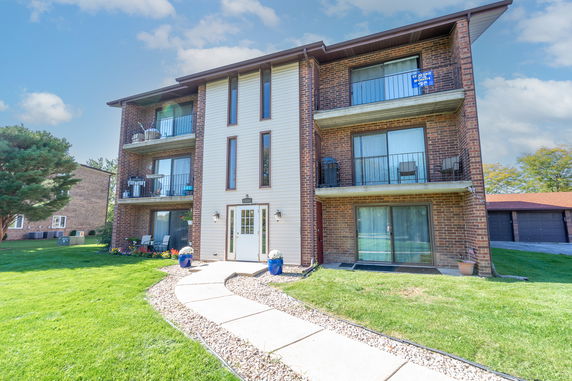 Front view of a three-story brick apartment building with balconies.