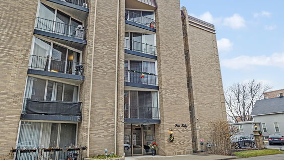 Front view of a multi-story brick apartment building with balconies.