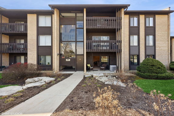 Front view of a multi-story residential building with balconies and large windows.
