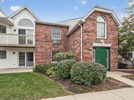 Front view of a two-story brick building with green door and arched windows.