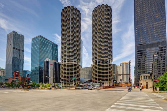 Front view of a cityscape with two distinct round skyscrapers and surrounding tall buildings.