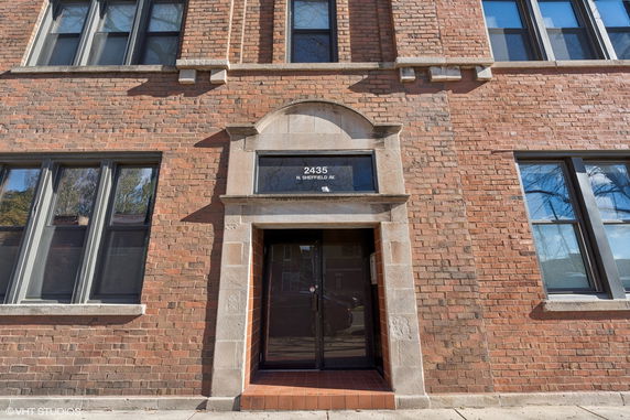 Front view of a brick building entrance with large windows.