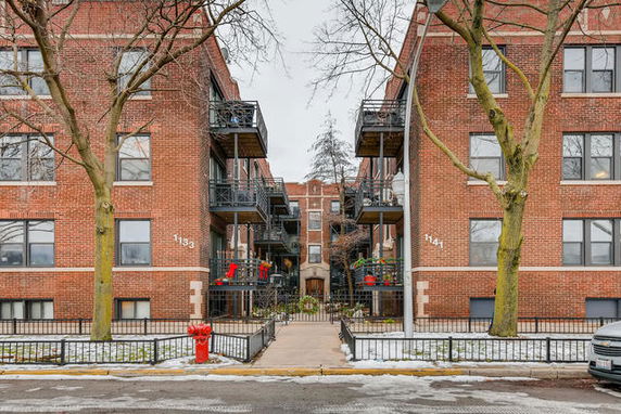 Front view of a multi-story brick apartment building with balconies.