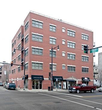 Front view of a four-story brick commercial building on a street corner.