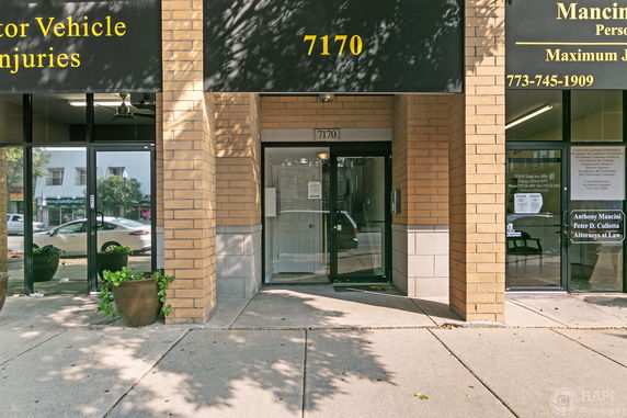 Entrance view of a brick commercial building with a glass door and signage.