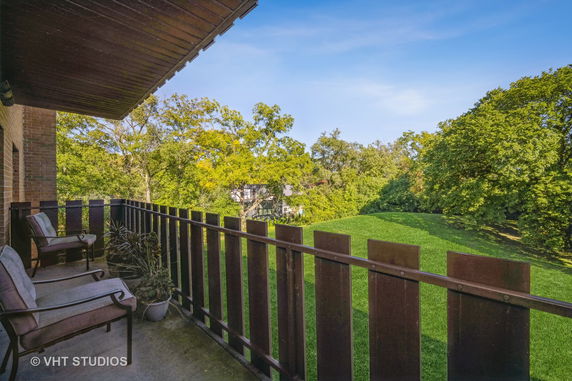 Patio view with railing overlooking green landscape and trees.