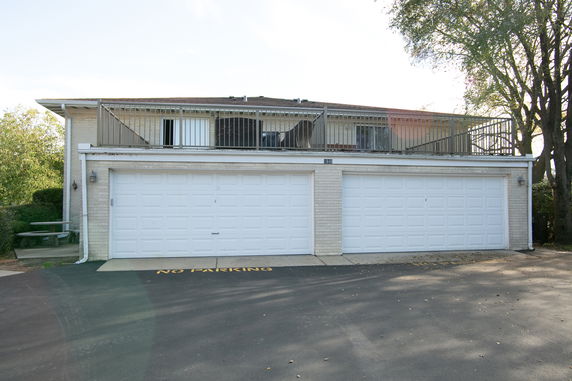 Front view of a two-story house with three white garage doors and a balcony above.
