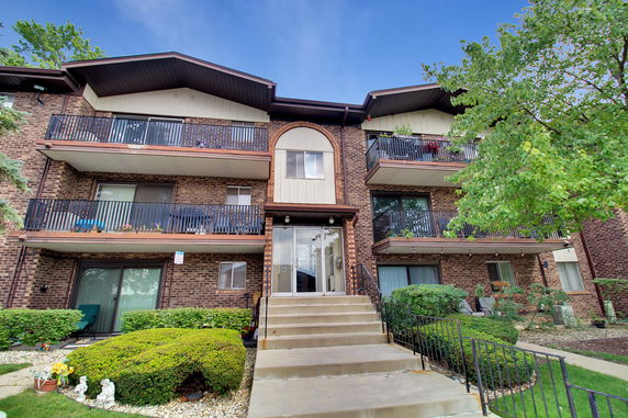 Front view of a multi-story brick residential building with balconies.