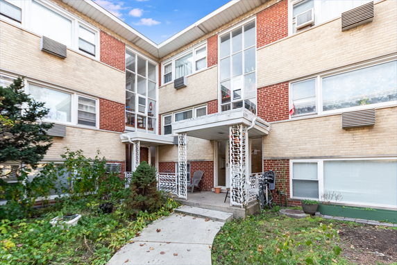 Front view of a multi-story apartment building with a central entrance and decorative columns.